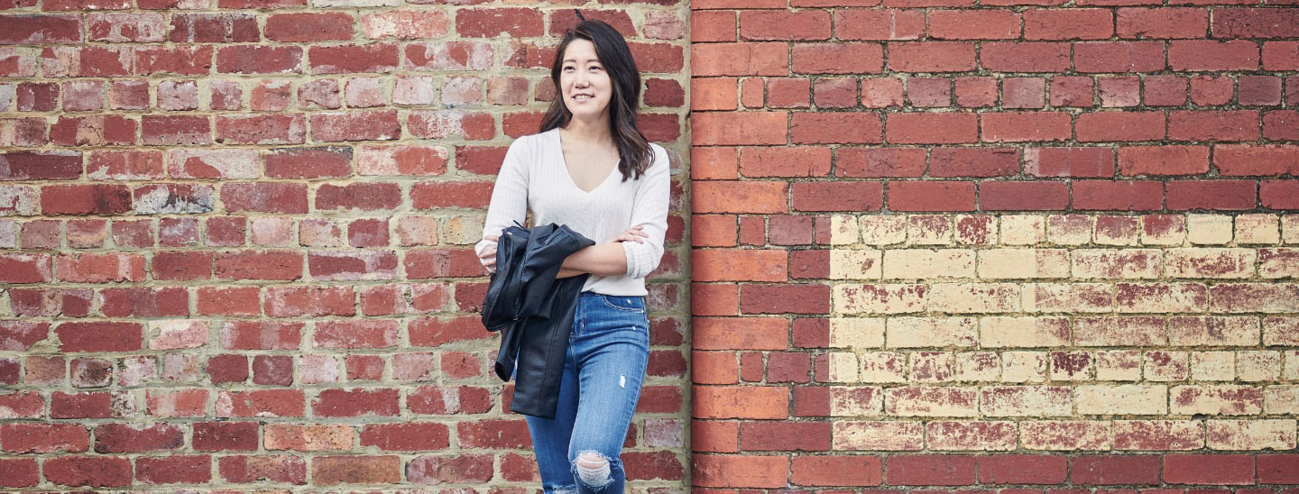 Asian female leaning on brick wall