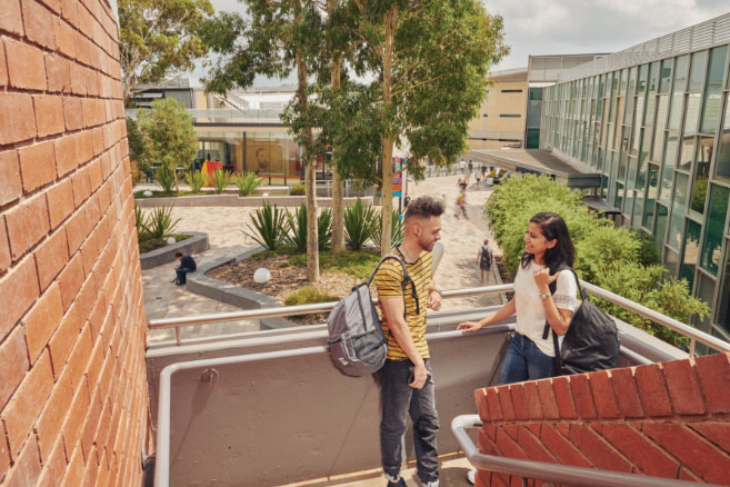 Campus couple standing on staircase outside brick building