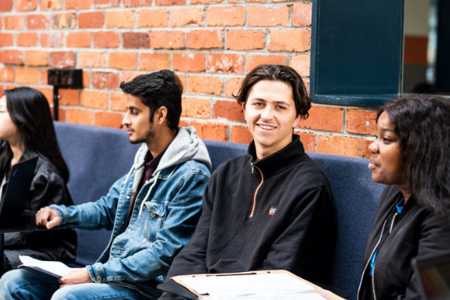 Campus group sitting on couch infront of red-brick wall