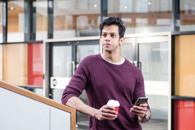 Male holding phone and coffee cup